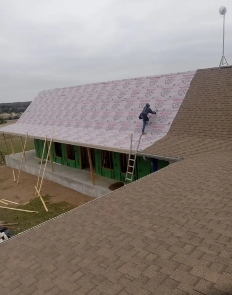 Worker preparing underlayment for a metal roof installation in Woodinville
